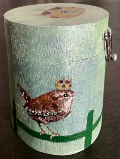 Una caja redonda de madera con un chochín paleártico con corona